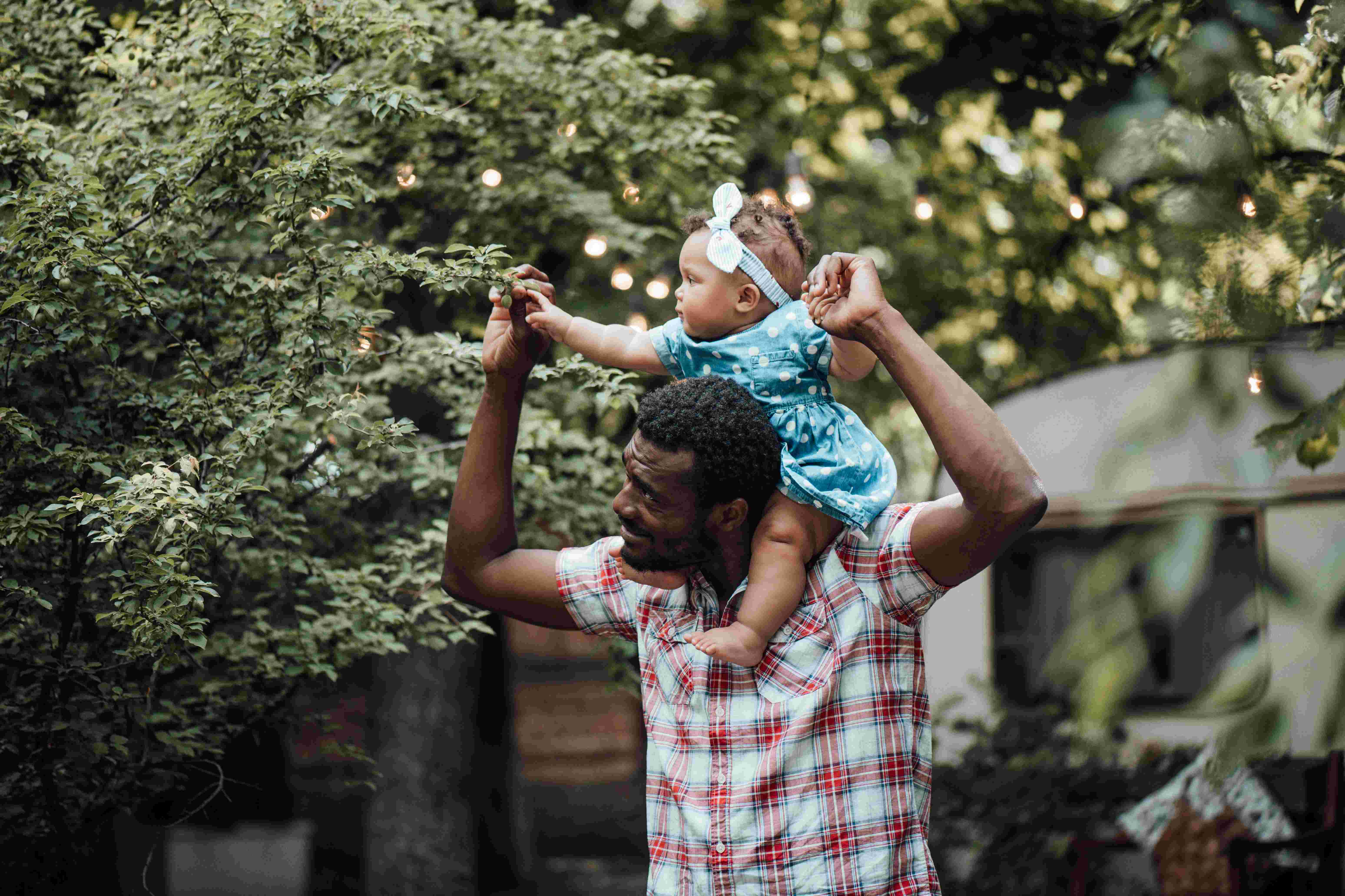 A father with his daughter on his shoulders, enjoying Father's Day activities for kids. 