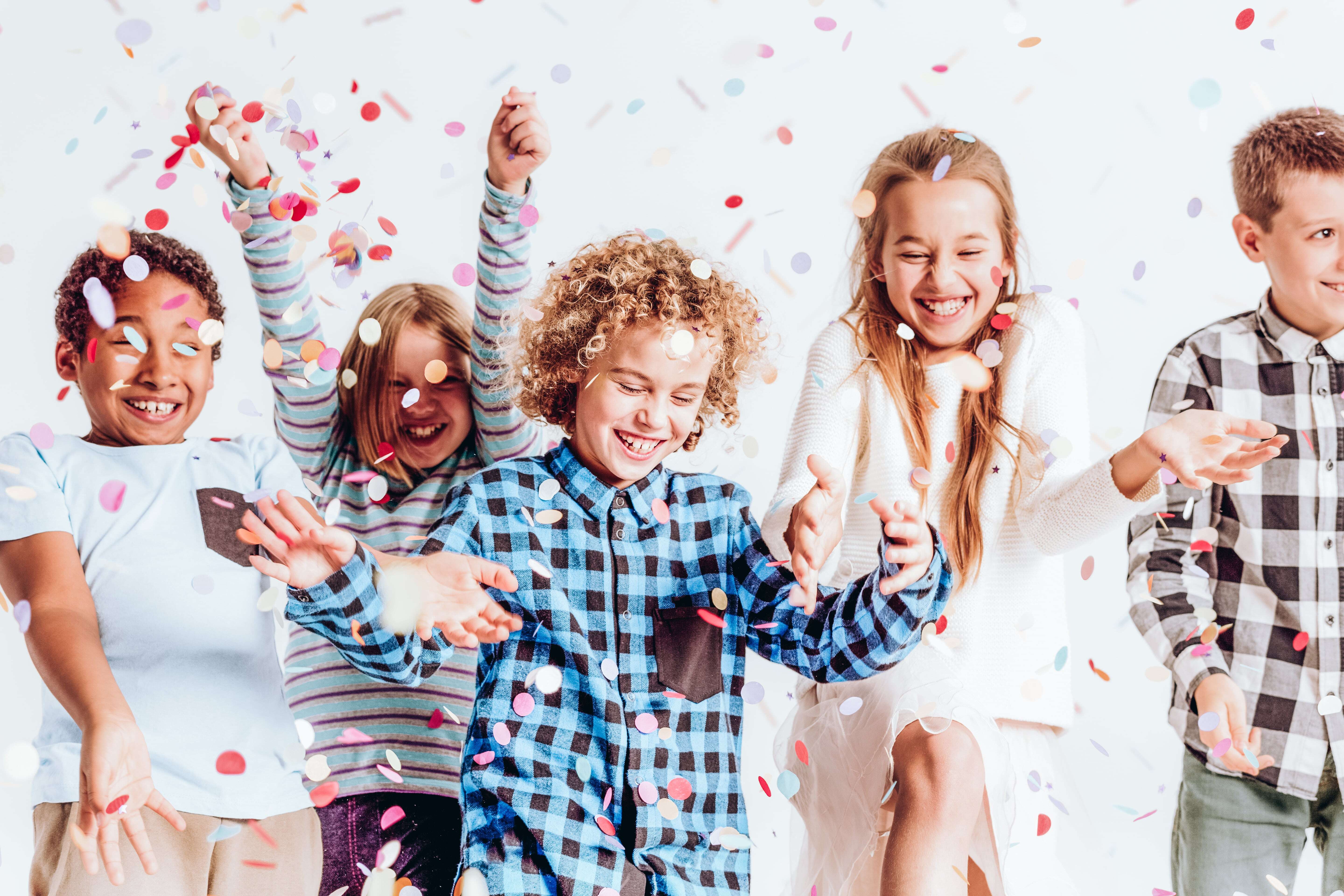 A group of children playing in confetti enjoying DIY New Year's Eve crafts for kids. 