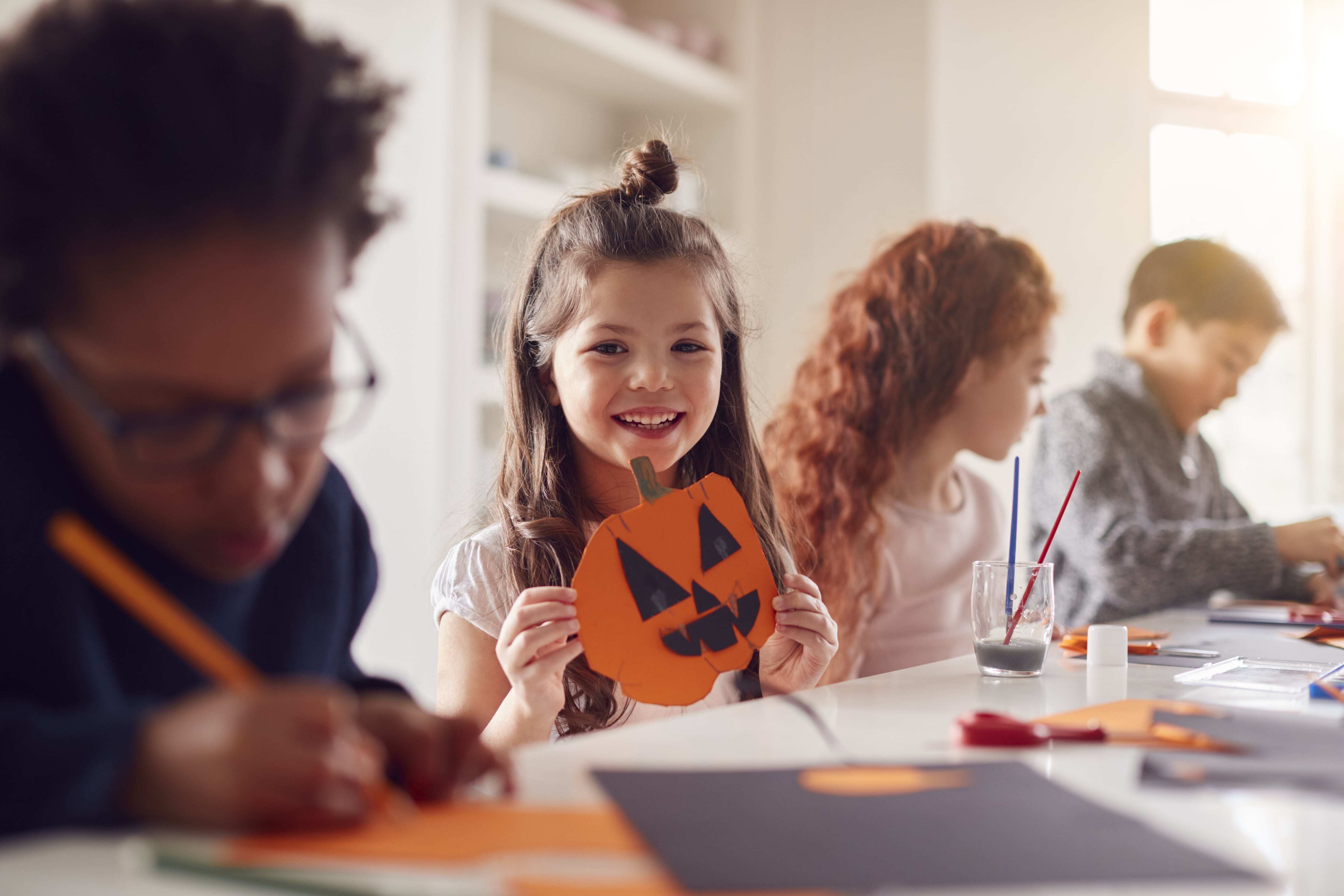 A group of children sitting together creating DIY Halloween decorations for kids.